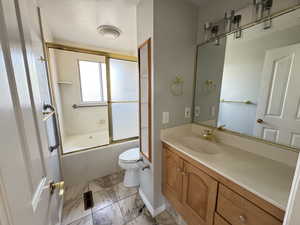 Full bathroom featuring bath / shower combo with glass door, vanity, and toilet