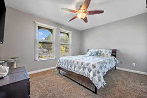 Carpeted bedroom featuring ceiling fan and a textured ceiling