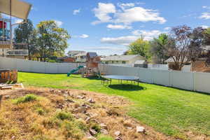 View of yard featuring a playground and a trampoline