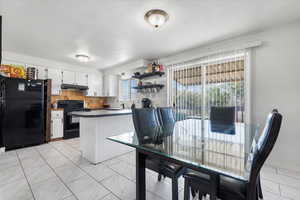 Kitchen with plenty of natural light, backsplash, black appliances, and white cabinetry