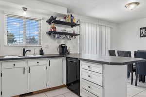 Kitchen with a breakfast bar, white cabinets, sink, kitchen peninsula, and dishwasher