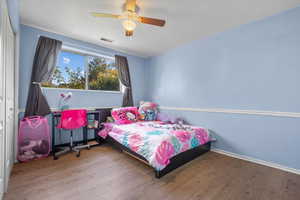 Bedroom with ceiling fan, a textured ceiling, a closet, and hardwood / wood-style floors