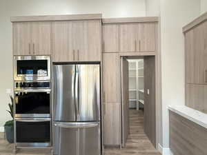 Kitchen with light stone countertops, appliances with stainless steel finishes, light hardwood / wood-style flooring, and light brown cabinetry