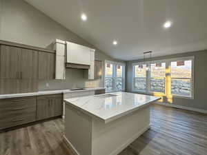 Kitchen with plenty of natural light, stovetop, light wood-type flooring, and vaulted ceiling