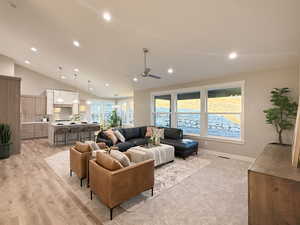 Living room with ceiling fan, light hardwood / wood-style floors, and vaulted ceiling