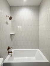 Bathroom with tiled shower / bath combo and toilet