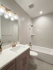 Full bathroom featuring tile patterned flooring, vanity, toilet, and tiled shower / bath