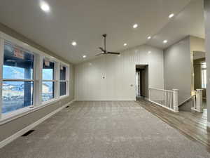 Unfurnished room with wood-type flooring, ceiling fan, and lofted ceiling