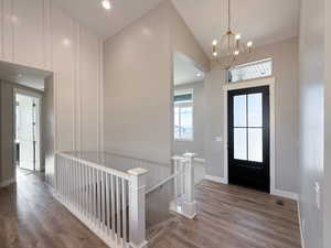 Entrance foyer with light hardwood / wood-style floors, lofted ceiling, and a notable chandelier