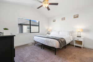 Carpeted bedroom with ceiling fan and vaulted ceiling