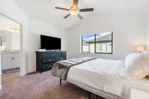 Bedroom with connected bathroom, light hardwood / wood-style floors, vaulted ceiling, and ceiling fan