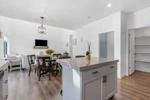 Kitchen featuring gray cabinets, light hardwood / wood-style flooring, a kitchen island, and decorative light fixtures