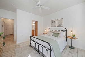 Bedroom featuring ensuite bathroom, ceiling fan, and light hardwood / wood-style flooring