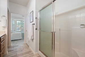 Bathroom with a shower with shower door, vanity, and hardwood / wood-style flooring