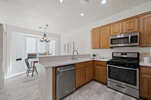 Kitchen featuring light hardwood / wood-style flooring, a notable chandelier, sink, stainless steel appliances, and kitchen peninsula