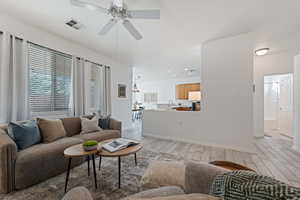 Living room with ceiling fan with notable chandelier, light hardwood / wood-style flooring, and sink