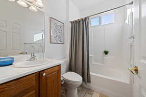 Full bathroom with vanity, toilet, shower / bathtub combination with curtain, and hardwood / wood-style flooring