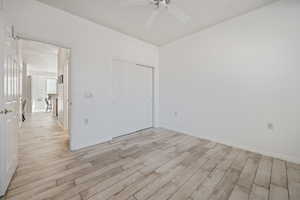 Unfurnished bedroom featuring a closet, light wood-type flooring, and ceiling fan