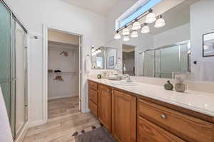 Bathroom featuring hardwood / wood-style flooring, vanity, and a shower with shower door