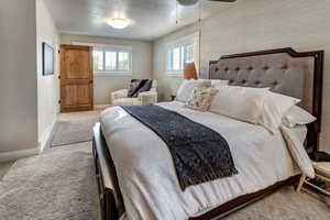 One of two owner's suites. Bedroom featuring light carpet, a textured ceiling, and ceiling fan