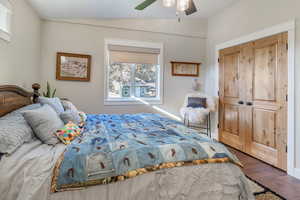 One of two owner's suites. Bedroom featuring a closet, vaulted ceiling, dark hardwood / wood-style flooring, and ceiling fan