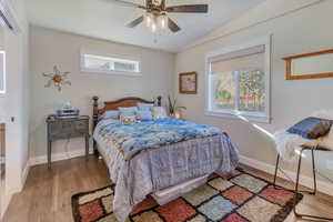 Bedroom featuring vaulted ceiling, multiple windows, ceiling fan, and hardwood / wood-style floors