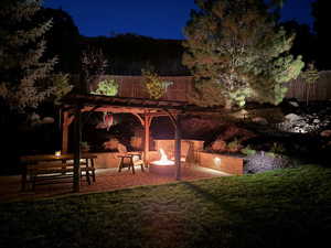 Patio at night with an outdoor fire pit and a pergola