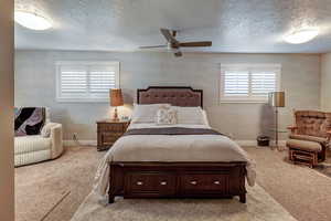 One of two owner's suites. Carpeted bedroom with ceiling fan and a textured ceiling