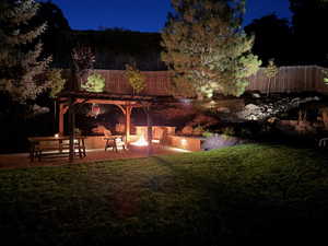 Patio at night with an outdoor fire pit and a pergola