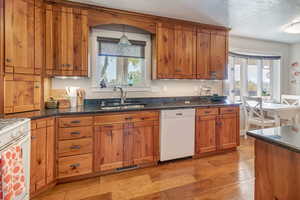 Kitchen featuring sink, plenty of natural light, light hardwood / wood-style floors, and white appliances