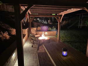 Patio at night with an outdoor fire pit and a pergola