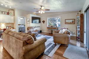 Living room with lofted ceiling, ceiling fan, dark hardwood / wood-style floors, and a textured ceiling