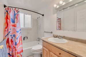 Full bathroom with tile patterned floors, vanity, toilet, and shower / bath combo with shower curtain