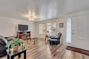 Living room with a chandelier, a textured ceiling, and hardwood / wood-style flooring