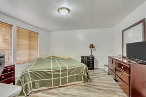 Bedroom with light wood-type flooring and a textured ceiling