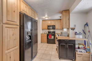 Kitchen featuring black appliances, light brown cabinets, light tile patterned flooring, and butcher block counters