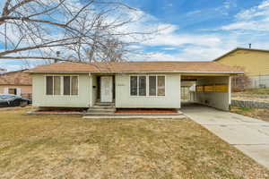 Ranch-style home featuring a carport and a front yard