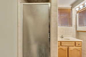 Bathroom featuring vanity, an enclosed shower, and tile walls