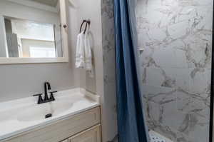 Bathroom featuring walk in shower, vanity, and ornamental molding