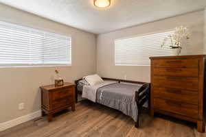 Bedroom featuring multiple windows, wood-type flooring, and a textured ceiling