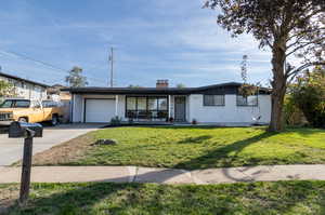 Ranch-style home featuring a front yard, a garage, and covered porch