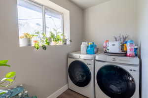 Clothes washing area with washing machine and clothes dryer and dark hardwood / wood-style flooring