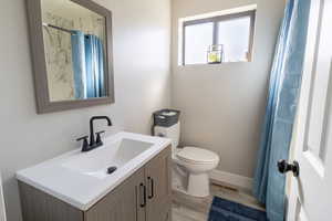 Bathroom with hardwood / wood-style floors, vanity, walk in shower, and toilet