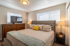 Bedroom with a textured ceiling and dark wood-type flooring