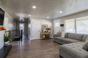 Living room featuring crown molding, dark wood-type flooring, and a textured ceiling