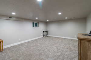 Basement featuring light colored carpet and a textured ceiling