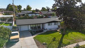 View of front of property with a garage, a porch, and a front lawn