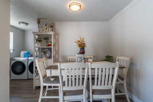 Dining area featuring a textured ceiling, crown molding, independent washer and dryer, and dark hardwood / wood-style flooring