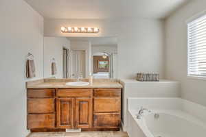 Primary Bathroom featuring vanity, tiled bath, and a wealth of natural light