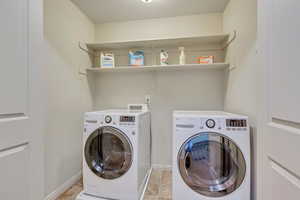 Laundry room with washer and clothes dryer and light tile patterned flooring right next to the bedrooms for ultimate convenience.